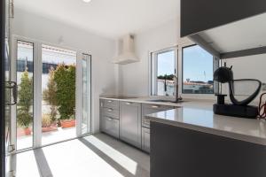 uma cozinha com balcões brancos e janelas com vista em Caparica Dream Vila em Costa da Caparica