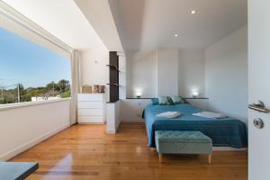 a bedroom with a blue bed and a large window at Caparica Dream Vila in Costa da Caparica