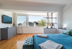 1 dormitorio con cama azul y ventana grande en Caparica Dream Vila en Costa da Caparica