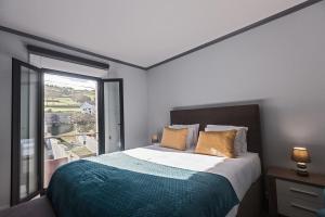- une chambre avec un lit et une grande fenêtre dans l'établissement Os Ninhos dos Avôs, à Ponta Delgada