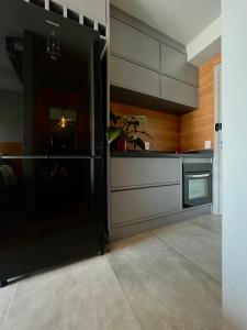 La cuisine est équipée d'un réfrigérateur noir et de placards en bois. dans l'établissement Studio Apartamento - Bela Vista São Paulo Centro, à São Paulo