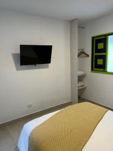 1 dormitorio con TV de pantalla plana en la pared en La posada de Rubi, en Salento