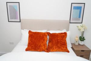 uma cama branca com duas almofadas cor-de-laranja em Exquisite- stylish- luxurious 2 bed apartment em The Hyde