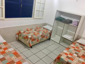 a room with two beds and a cabinet in it at Pousada Bem Brasil in Macaé