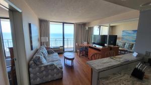 a living room with a couch and a table and a television at Four Sails Resort in Virginia Beach