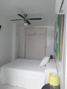 a bedroom with a white bed with a ceiling fan at PAUPET in Almería