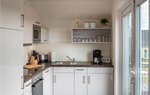 Una cocina con gabinetes blancos y un fregadero y una ventana. en Cozy Apartment In Büsum With Sauna, en Büsum