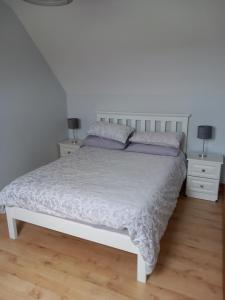 a bedroom with a white bed with two night stands at Larchlodge in Ennis