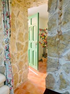 Habitación con pared de piedra y puerta verde. en Cueva Colorin Alloza., en Alloza