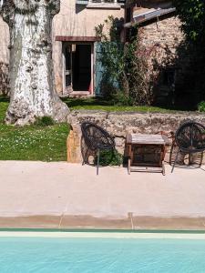 a picnic table and two chairs next to a pool at Le havre du voyageur in Charly