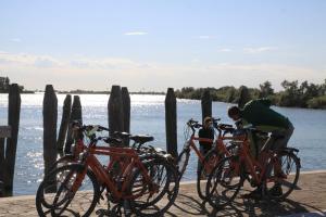 Un hombre inclinado sobre una fila de bicicletas junto al agua. en Hotel El Paso, en Lido di Jesolo