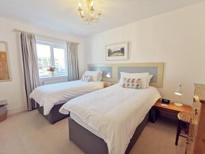a bedroom with two beds and a desk and a window at CYNEFIN- 3 Bed, 2 Bath-1 x En-Suite, DETCAHED BUNGLAOW- PET FRIENDLY in Trearddur