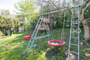 a swing in a yard with a ladder and a tree at Squash Apartments & Studios in Siófok