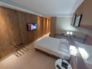 a bedroom with a bed and a tv on a wall at Mar Premier Flats OFICIAL Queimados RJ in Queimados