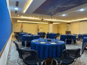 uma sala de conferências com mesas azuis e cadeiras em Hotel Nova Sky em Erbil