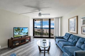 a living room with a blue couch and a tv at Beachfront I Full Coastal Contemporary Renovation in Marco Island