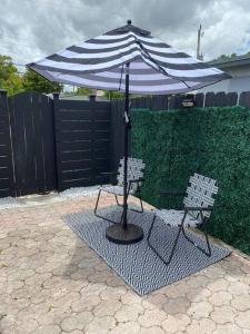 a black and white umbrella and two chairs under it at PRIVATE Cozy Guest Suite Near Hard Rock Guitar in Fort Lauderdale