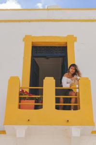 a woman sitting on a balcony looking out of a window at Hostal 1545 in Ríohacha