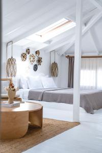 a white bedroom with a large bed and a table at Kurabiye Hotel in Alacati