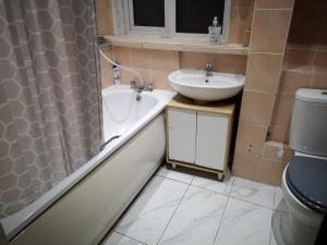 uma casa de banho com um lavatório, uma banheira e um WC. em White House "Luton Airport" em Luton