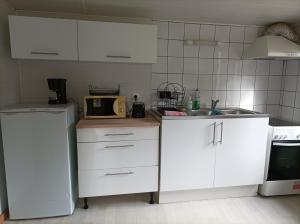 cocina con armarios blancos, fregadero y microondas en Chez Julien et Mélanie, en La Frugerie