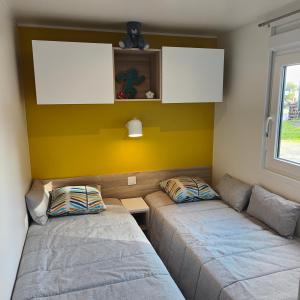 sala de estar con 2 camas y pared amarilla en Le Colorful, en Dinard