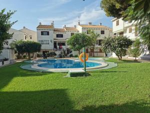 ein Schwimmbad in der Mitte eines Gartens mit Gebäuden in der Unterkunft Oleza Garden Village , Apartment Ines in Playa Flamenca
