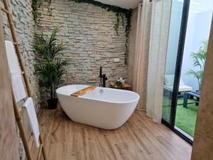 a white bath tub in a bathroom with a brick wall at BALI Ubud in Cómpeta