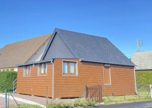 een houten huis met een zwart dak bij Chaleureux chalet en bord de mer in Merville-Franceville-Plage