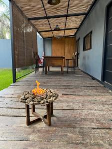 una hoguera en una terraza de madera con una mesa en Chana's House en Chascomús