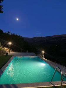 a swimming pool at night with the moon in the sky at Casa do Tapadinho in Ribeira de Pena