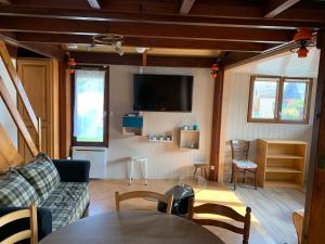 a living room with a couch and a tv at Chaleureux chalet en bord de mer in Merville-Franceville-Plage
