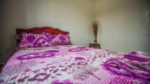 un letto con copriletto viola e fiori sopra. di Appartements Neuf de Haut Standing DM & NG à Bafoussam a Bafoussam