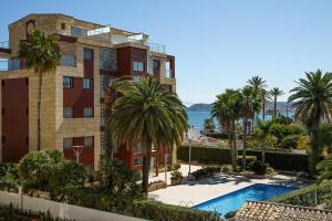 an apartment building with a swimming pool and palm trees at Port de Xabia I in Jávea