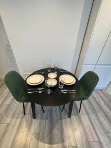a black table with green chairs and plates and wine glasses at Seaforth Deluxe 2 bedroom apartment at Rockman Luxury Short Stays Lets and Accommodation in Southend-on-Sea