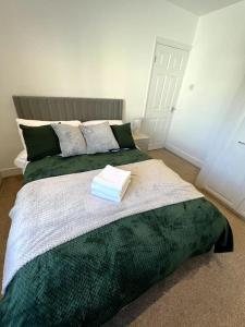 a bedroom with a large bed with a green blanket at Seaforth Deluxe 2 bedroom apartment at Rockman Luxury Short Stays Lets and Accommodation in Southend-on-Sea