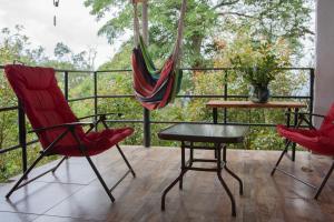 Un balcón con 2 sillas, una mesa y una hamaca. en Casa Hudié Campestre, en Cachipay