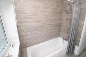 a bathroom with a bath tub with a shower at Business friendly 3BR home - King size beds & Centrally located in Swansea