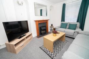 a living room with a television and a couch and a table at Business friendly 3BR home - King size beds & Centrally located in Swansea
