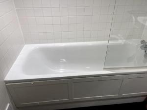 La salle de bains est pourvue d'une baignoire blanche et de carrelage blanc. dans l'établissement Sanctuary Spaces at The Shard with private parking, à Londres