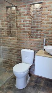 a bathroom with a white toilet and a brick wall at Hospedaje El Shadday in Taganga