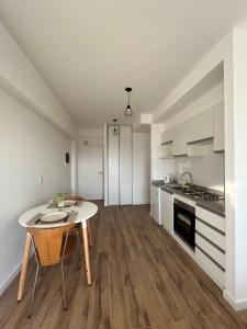 ブエノスアイレスにあるMonoambiente Urquizaの白いキャビネットとテーブル付きのキッチンが備わります。
