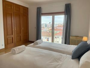 two beds in a bedroom with a large window at ASF Brasil in Lisbon