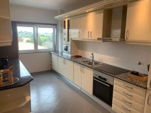 a kitchen with white cabinets and a sink and a window at ASF Brasil in Lisbon