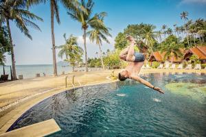 a man jumping into a swimming pool at a resort at Grand Sea Beach Resort in Haad Pleayleam