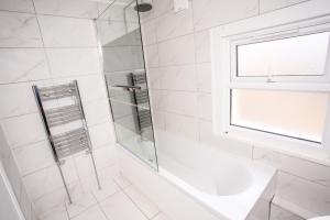 ein weißes Bad mit einer Dusche und einem Waschbecken in der Unterkunft Newly Refurbished 3 Bedroom House close to Central London in London