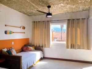 Un dormitorio con una cama y un ventilador de techo. en Suite Charme apt 10, en Ilhabela