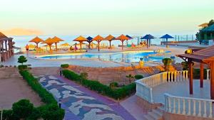 um resort com piscina, mesas e guarda-sóis em Halomy Sharm Resort em Sharm El Sheikk