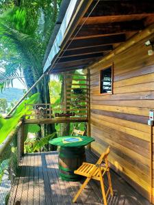 a wooden cabin with a table and a chair on a deck at Chalés Paris in Paraty