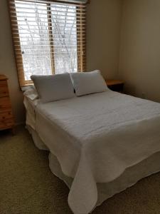 a bedroom with a bed with white sheets and a window at The Point - On Gull Lake in Brainerd